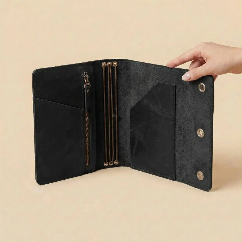 Black leather notebook held by a hand on a beige background