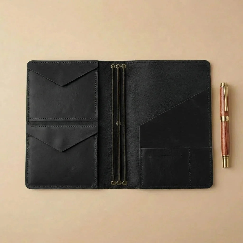 Black leather journal with a pen on a beige background