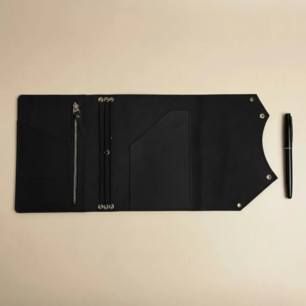 Black leather journal with a pen on a beige background