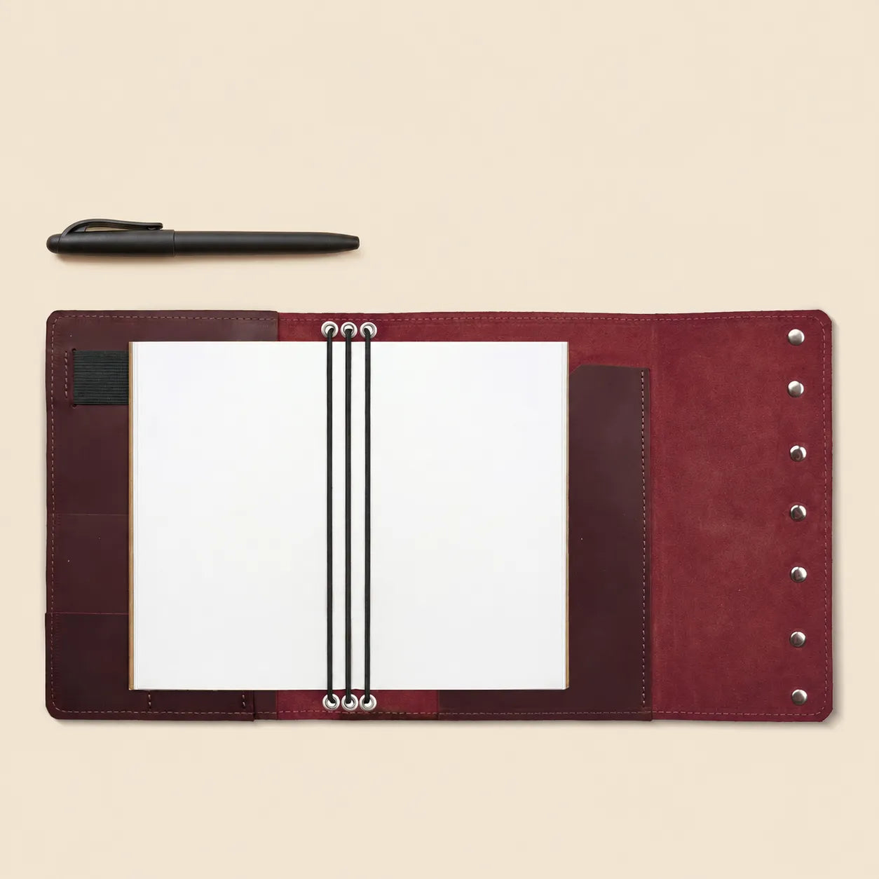 Refillable leather notebook case featuring organized pockets and secure pen loop.
