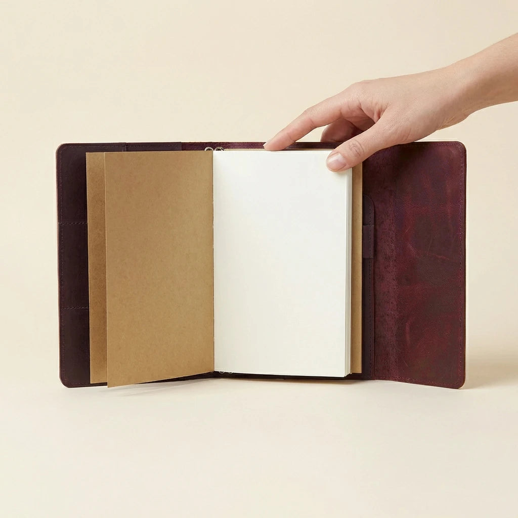 Hand holding a open leather-bound notebook against a beige background