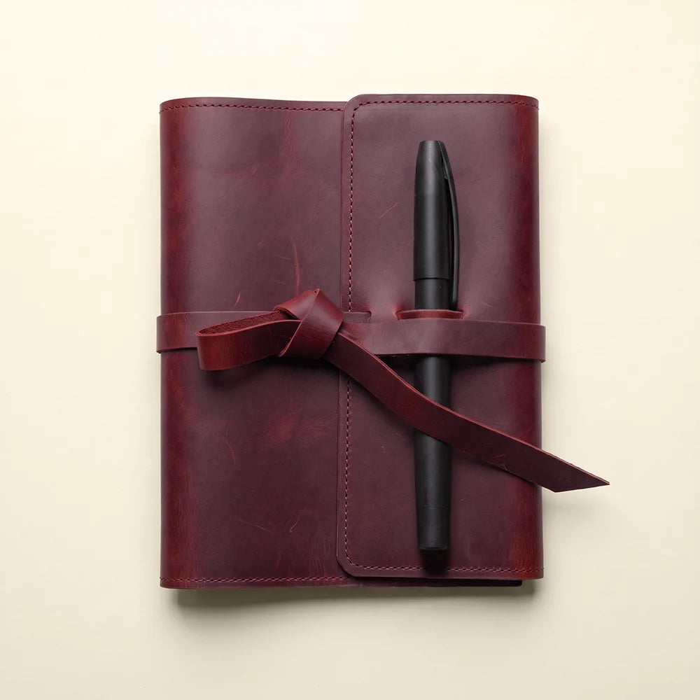 Genuine leather notebook sleeve with interior pockets and convenient pen loop.