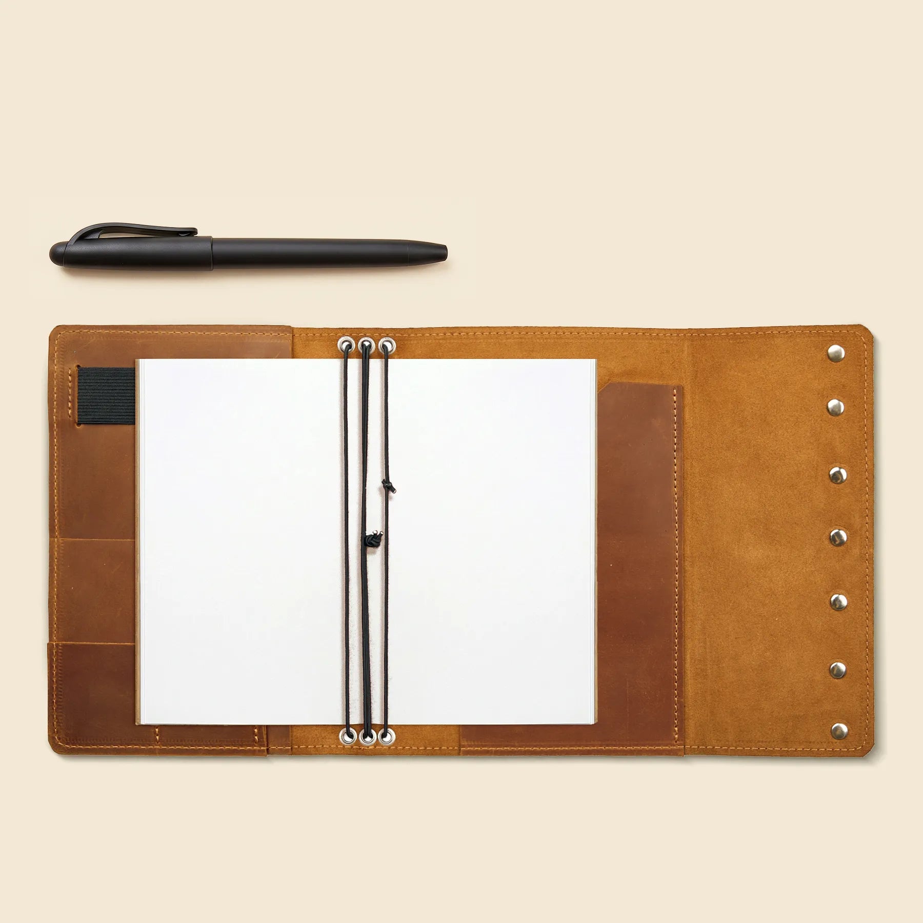 Leather traveler's notebook cover with pen holder and storage compartments.