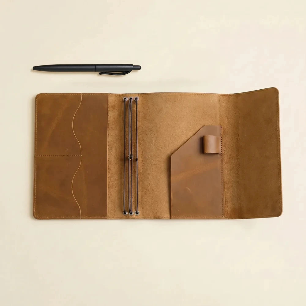 Refillable genuine leather notebook cover with secure elastic system and interior pocket organizer.