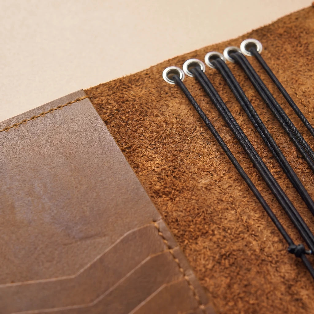 Handmade leather planner featuring multiple notebook elastics and storage