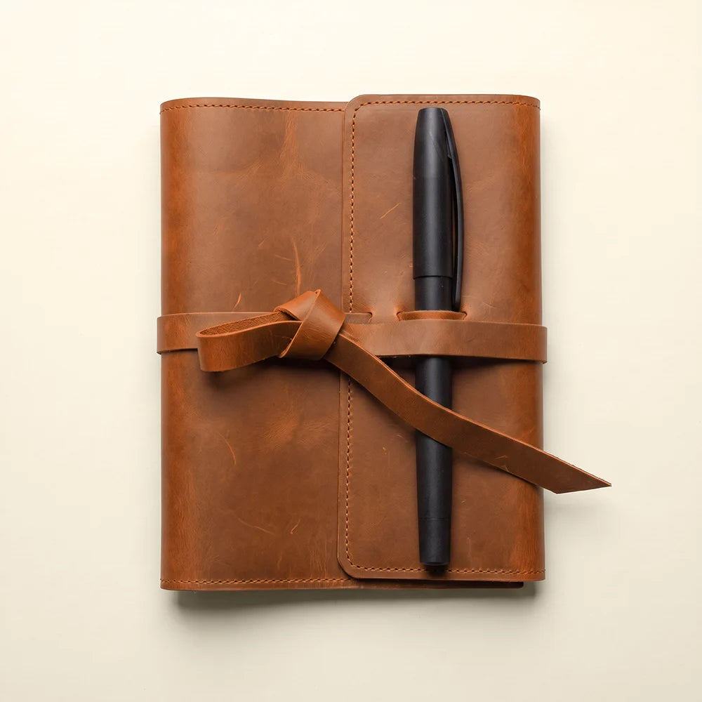 Premium leather notebook organizer with interior pockets and secure pen loop.