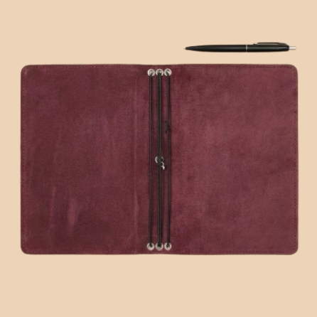 Brown leather notebook with a pen on a beige background
