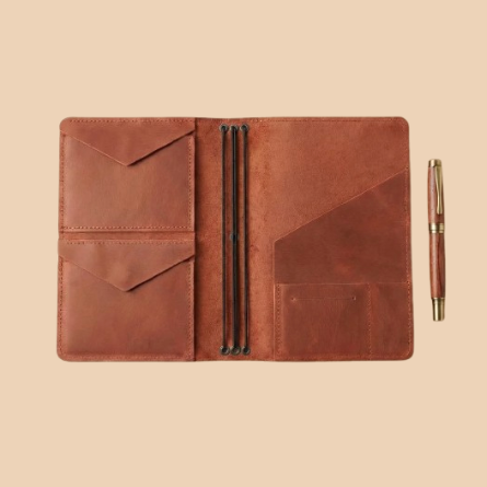 Brown leather journal cover with pen on a beige background