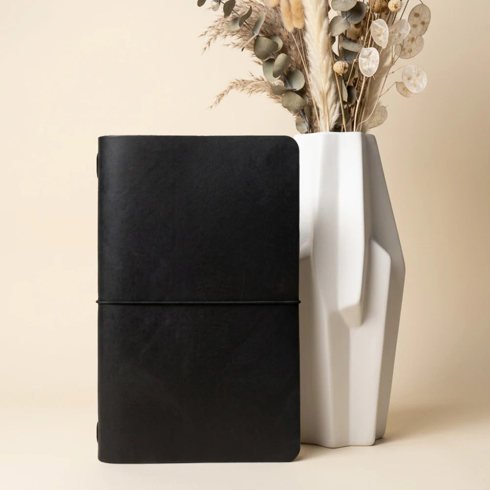 Handcrafted leather writing sleeve with clean stitching around a simple notebook.