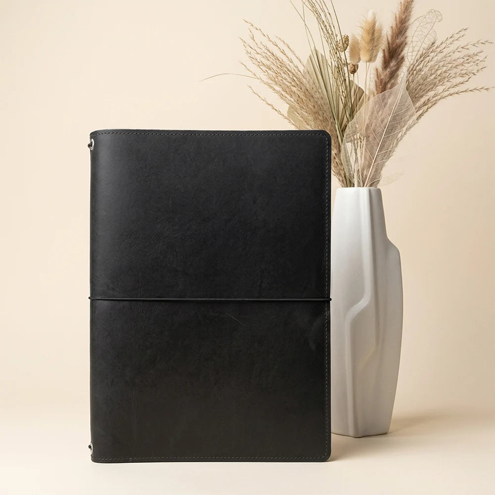 Leather notebook carrier featuring inner storage and flexible elastic support for inserts.