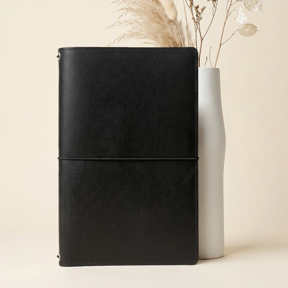 Handmade leather planner holder with elastic retainers for multiple refillable notebook inserts.