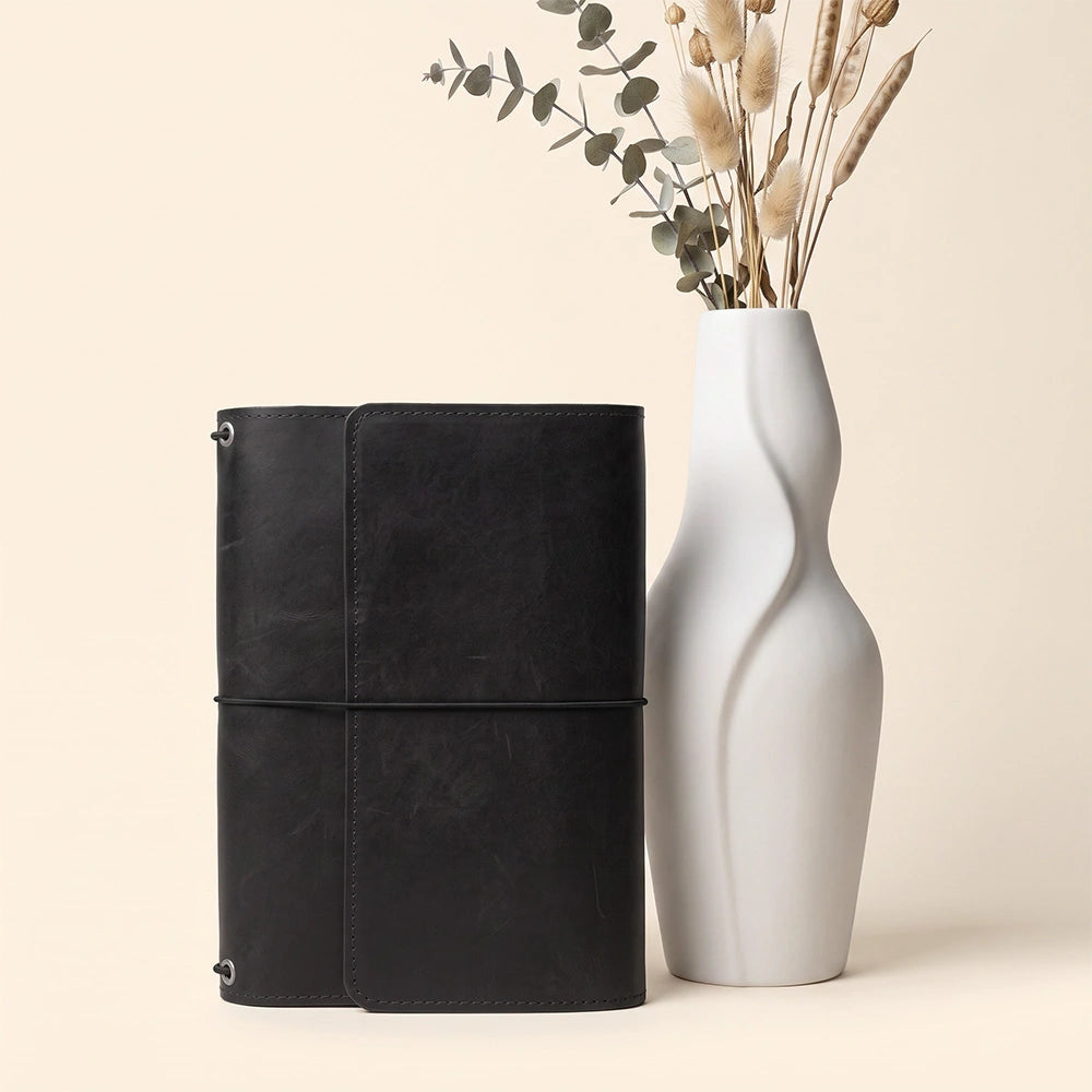 Handmade leather journal folder with functional compartments and integrated writing instrument holder.