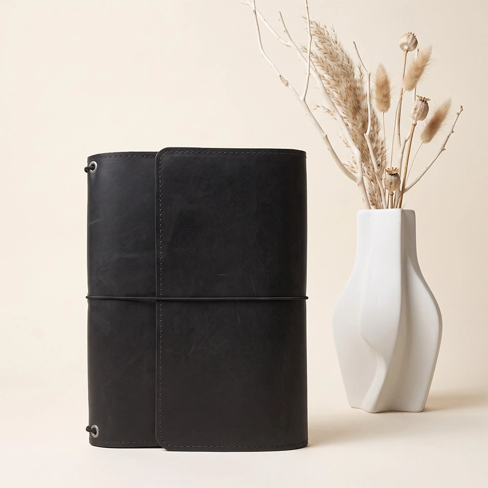 Leather notebook folder with spacious interior storage and secure pen retaining loop included.