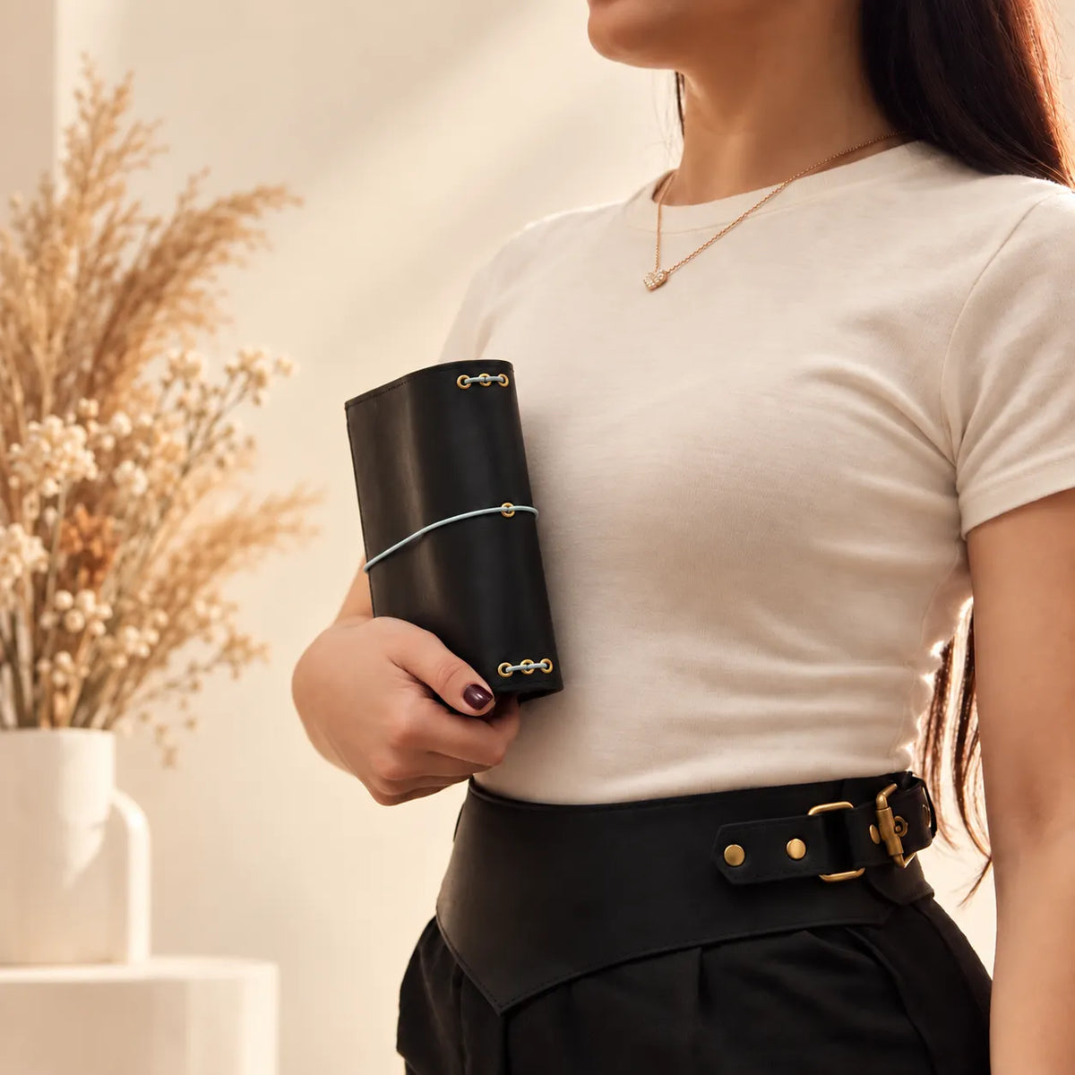 Young woman presenting a genuine leather journal cover with natural grain and warm texture.