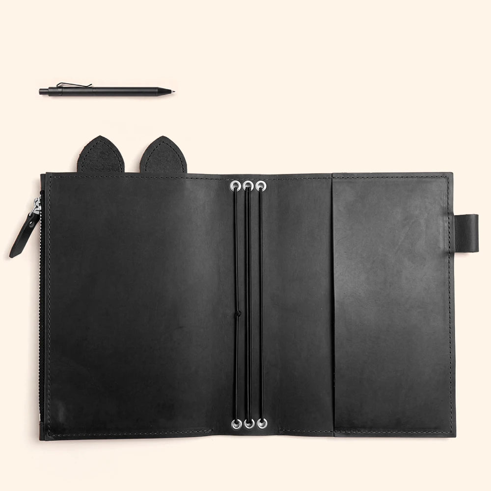 Open leather writing organizer featuring a dedicated pen holder beside interior storage.