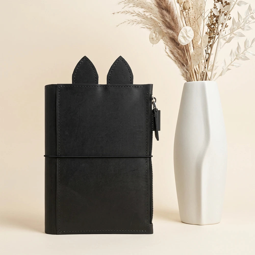 Open leather organizer displaying spacious zippered storage and handcrafted decorative ear tabs.