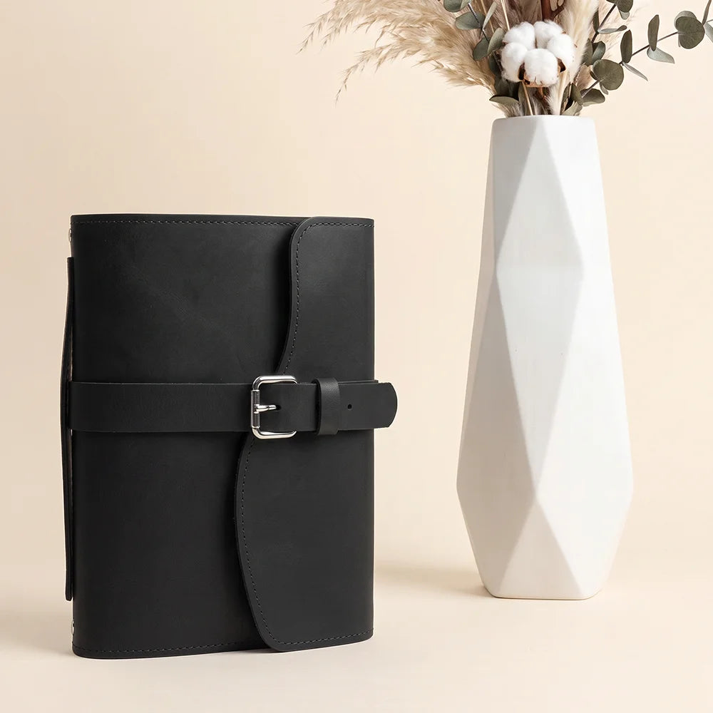 Genuine hide journal holder showcasing inner pockets, elastic pen loop, sewn bookmark ribbon, and convenient outer grip.
