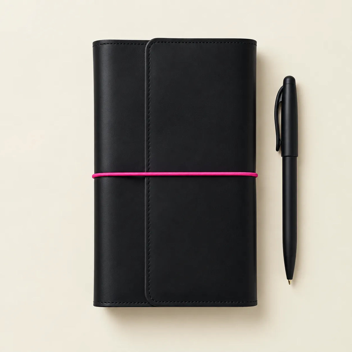 Stylish black leather notebook cover accented with vibrant pink elastic bands