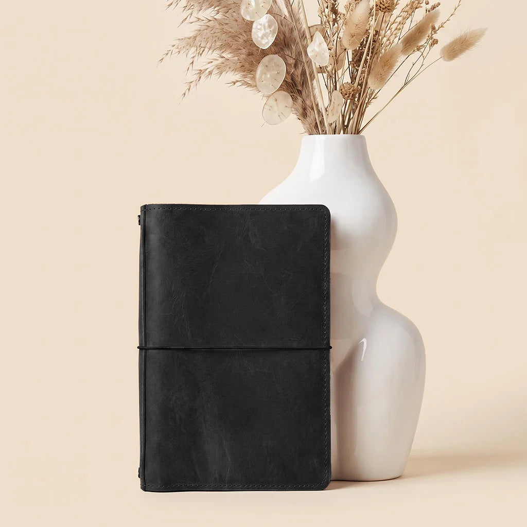 Leather notebook cover displaying organized pockets and flexible elastic bands for notebook inserts.