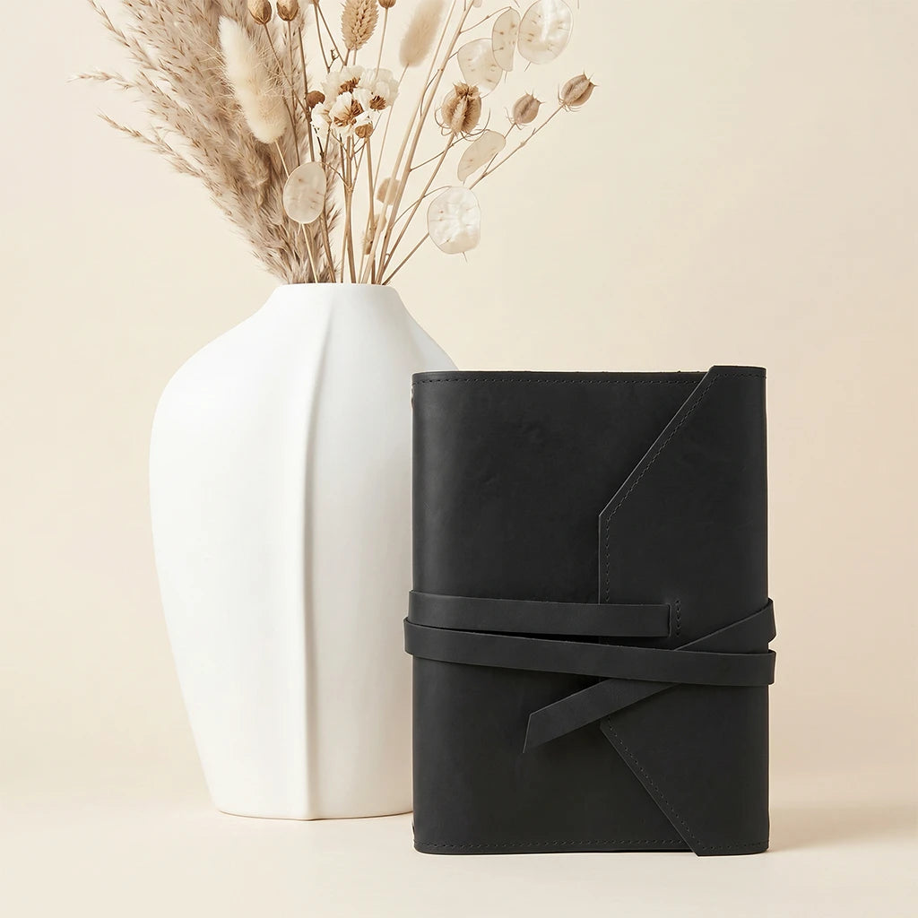 Protective leather notebook sleeve with organized pen storage and closure.