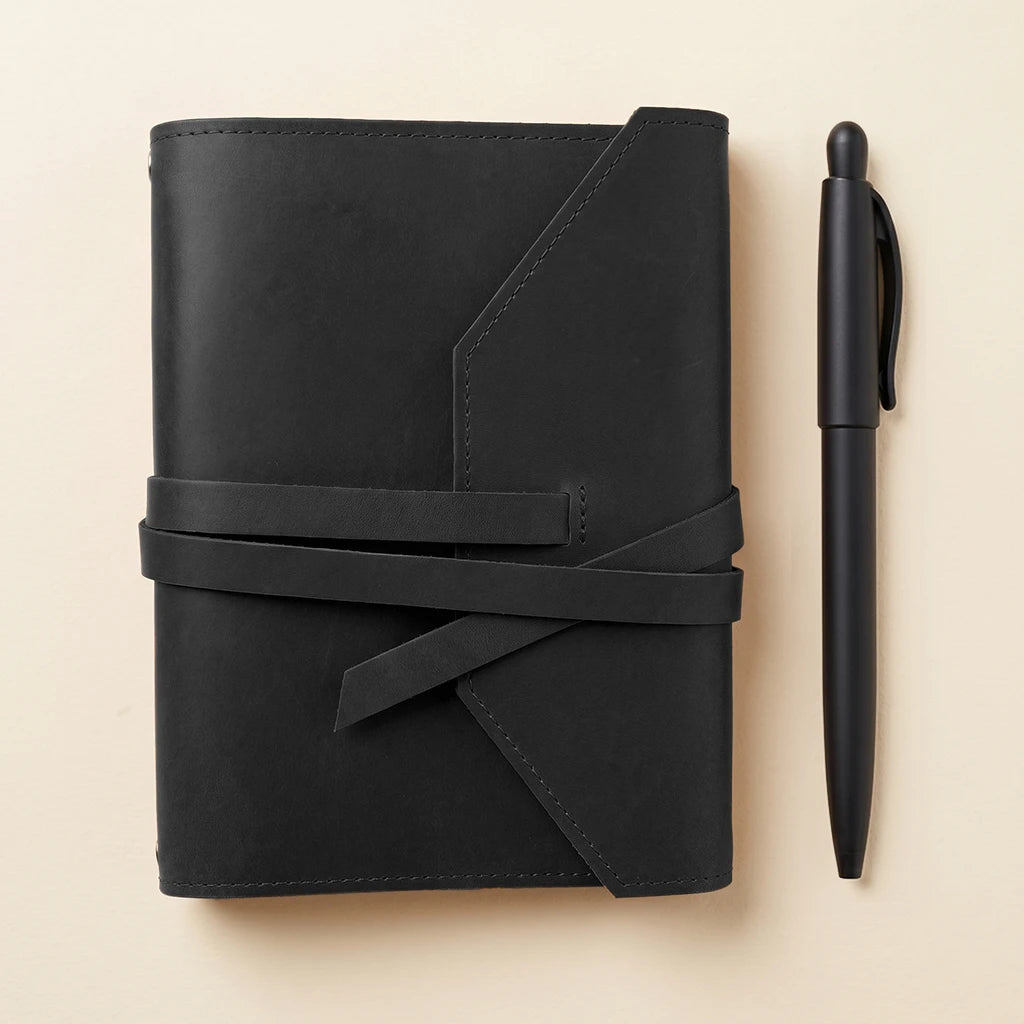 Refillable leather notebook holder with elastic straps and pen loop feature.