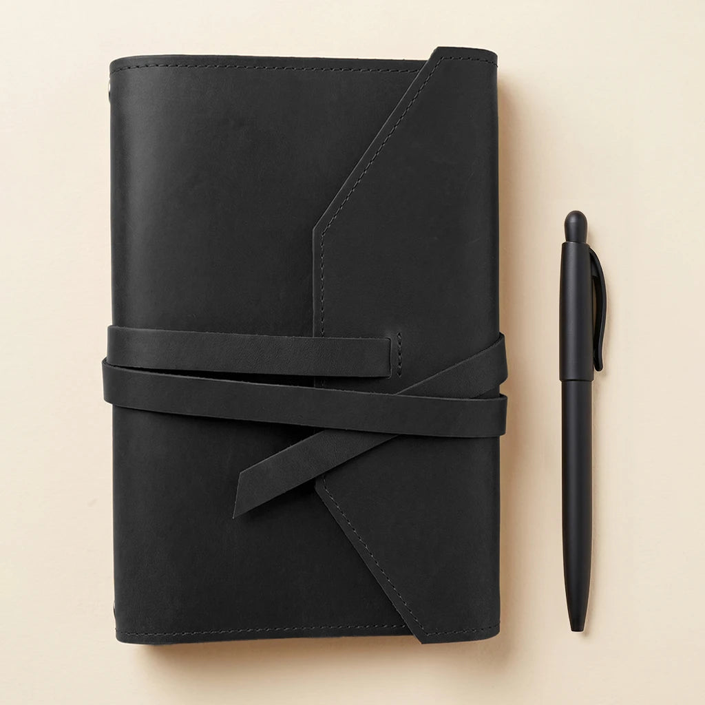 Refillable leather cover for journals with elastic fastening and pen holder detail.