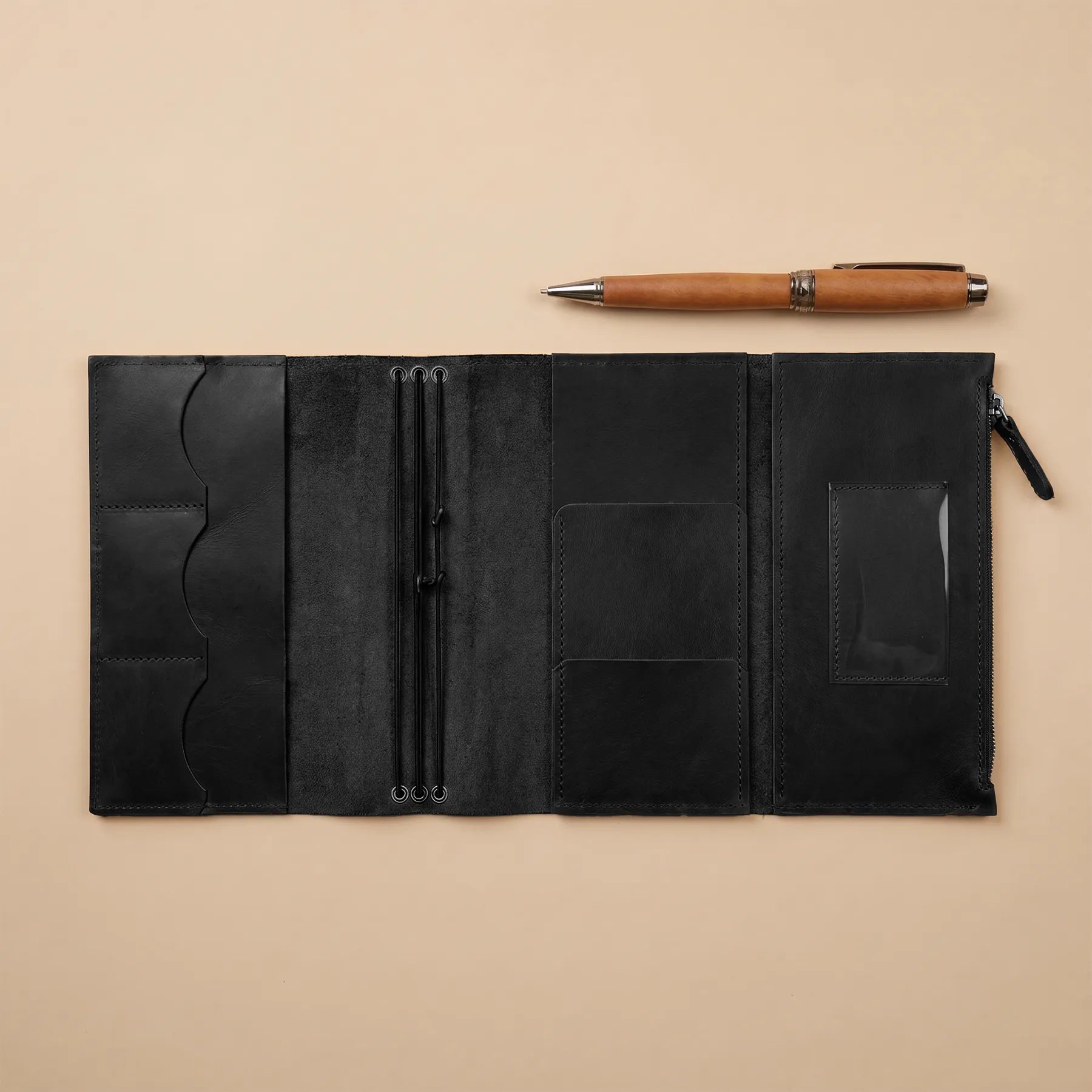 Black leather journal with pen on a beige background