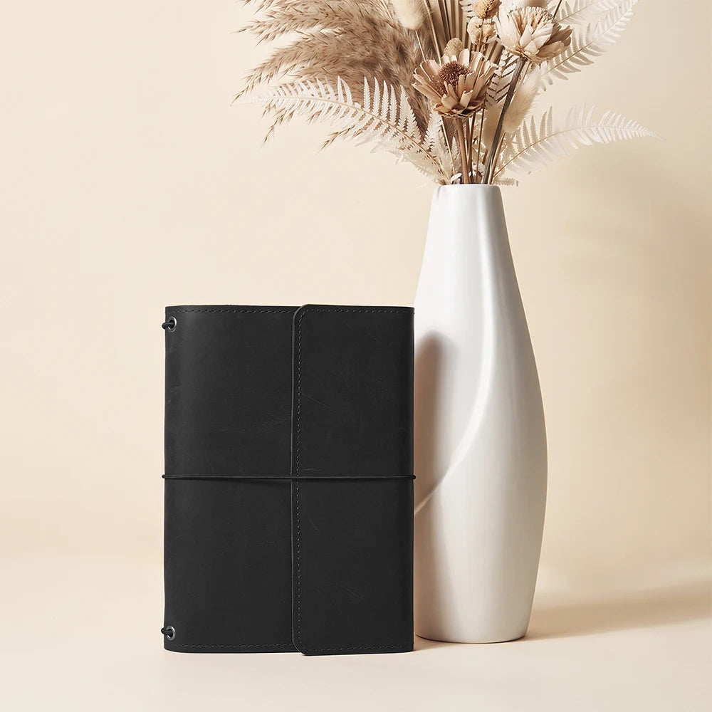 Leather notebook cover with practical refillable insert system and organized storage compartments inside.