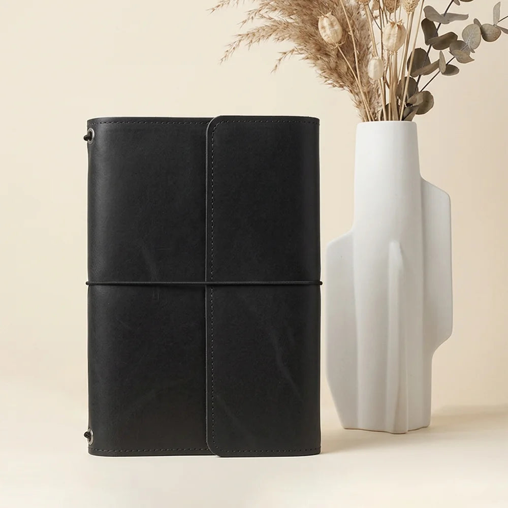 Natural leather journal case with stitched storage pockets and an integrated pen carrying loop.