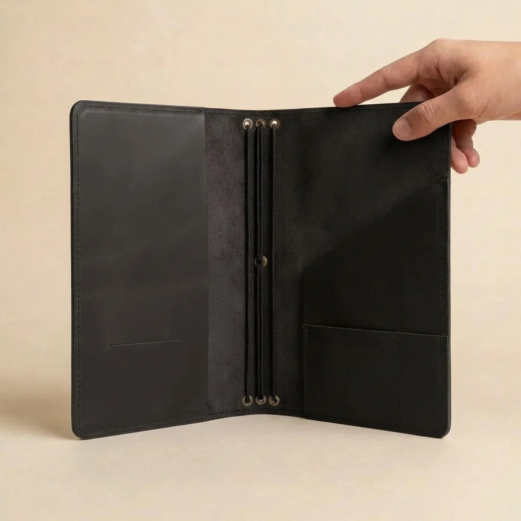 Black leather journal held open by a hand on a beige background