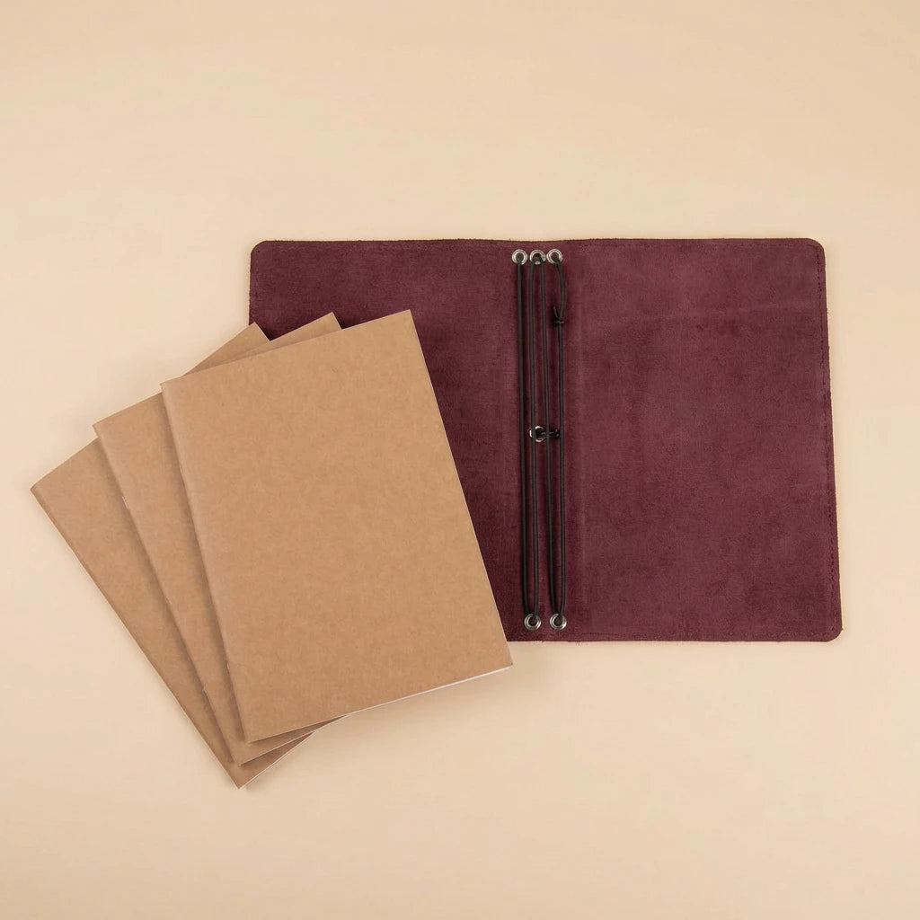 Brown leather-bound notebooks with a burgundy leather cover on a beige background