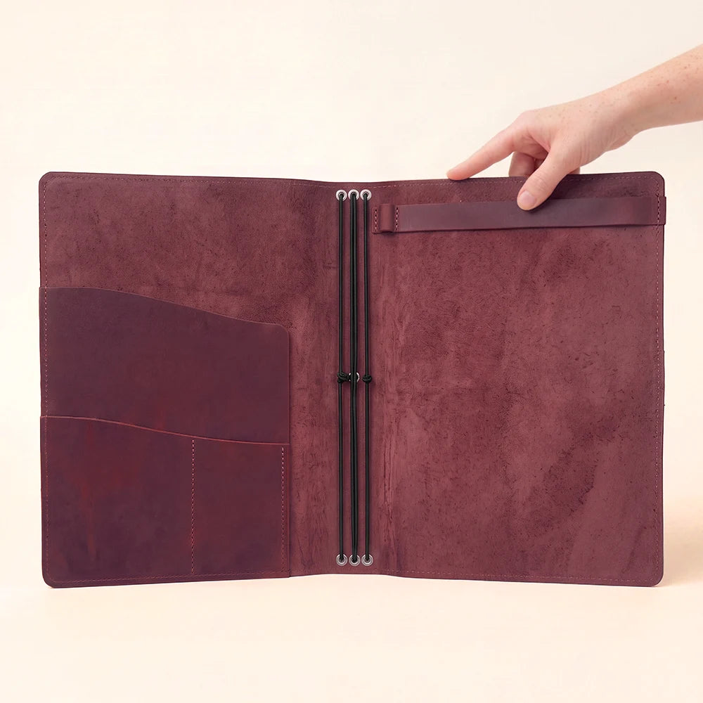Handmade leather writing case with organized pockets and elastic support for notebook inserts.