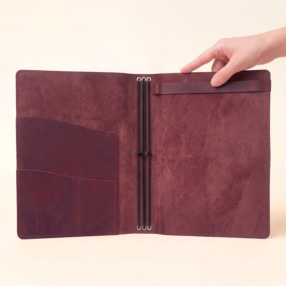 Leather stationery organizer with a sketchbook strap and elastic system for extra inserts.