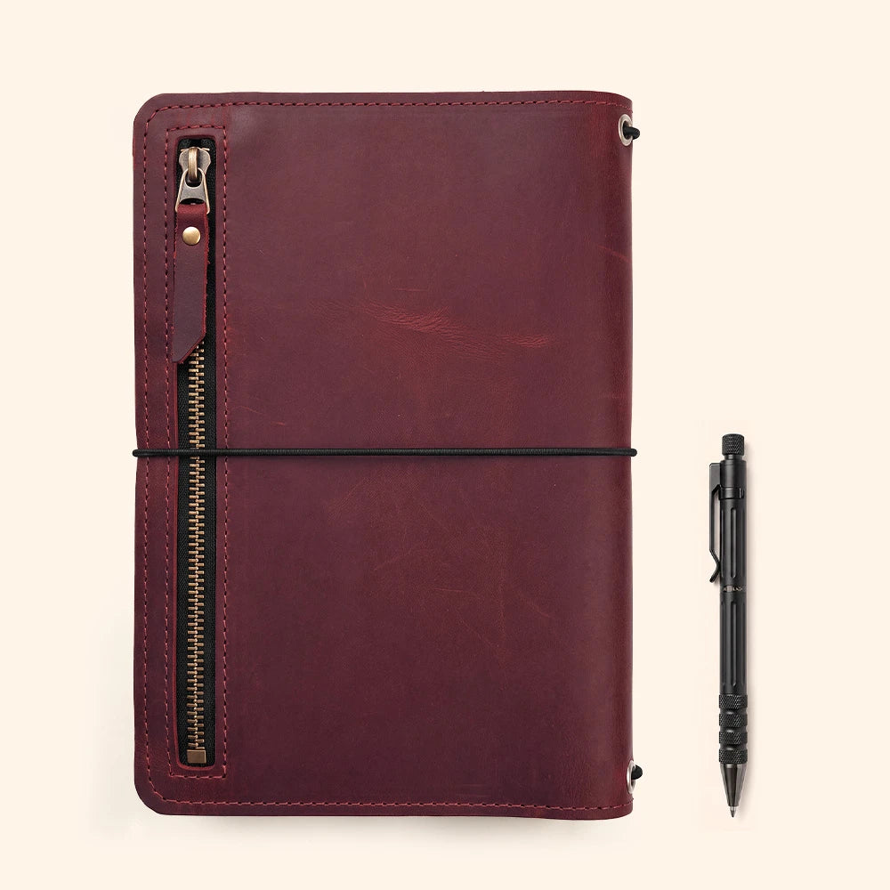 Natural leather journal organizer with interior storage features and attached writing tool loop.