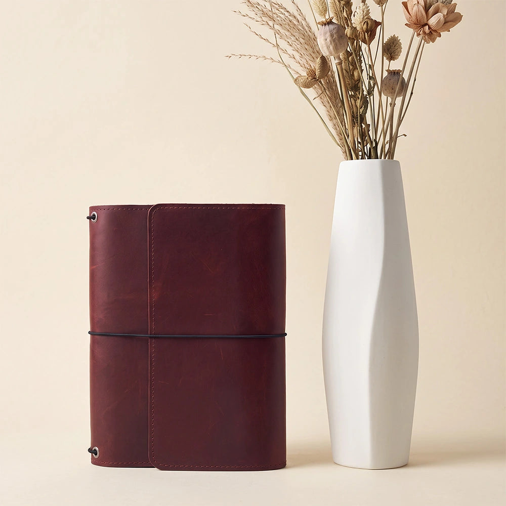 Handcrafted leather notebook case with multiple storage compartments and stitched pen holder.