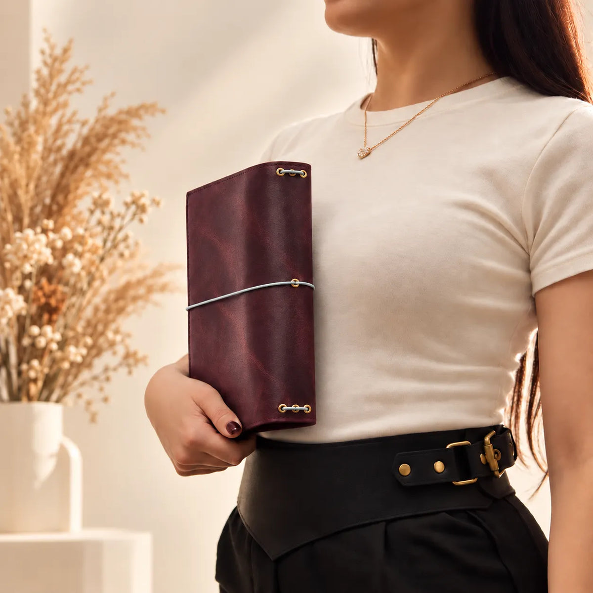 Woman holding a natural leather notebook cover, demonstrating its size and handcrafted appearance.