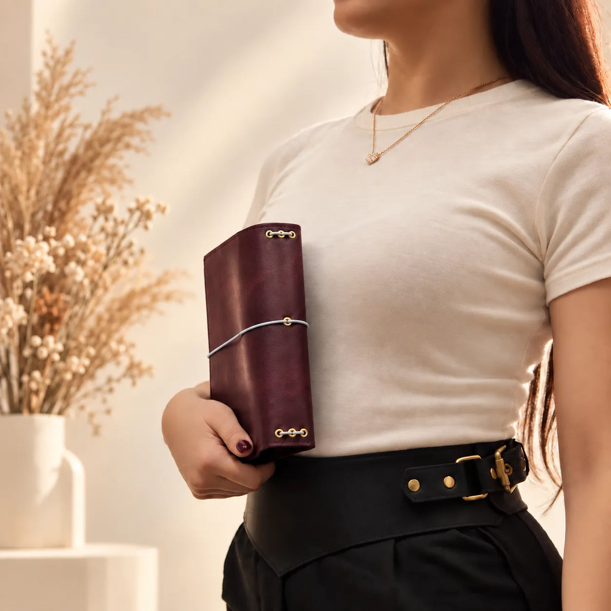 Young woman displaying a natural leather notebook cover with a classic handmade aesthetic.