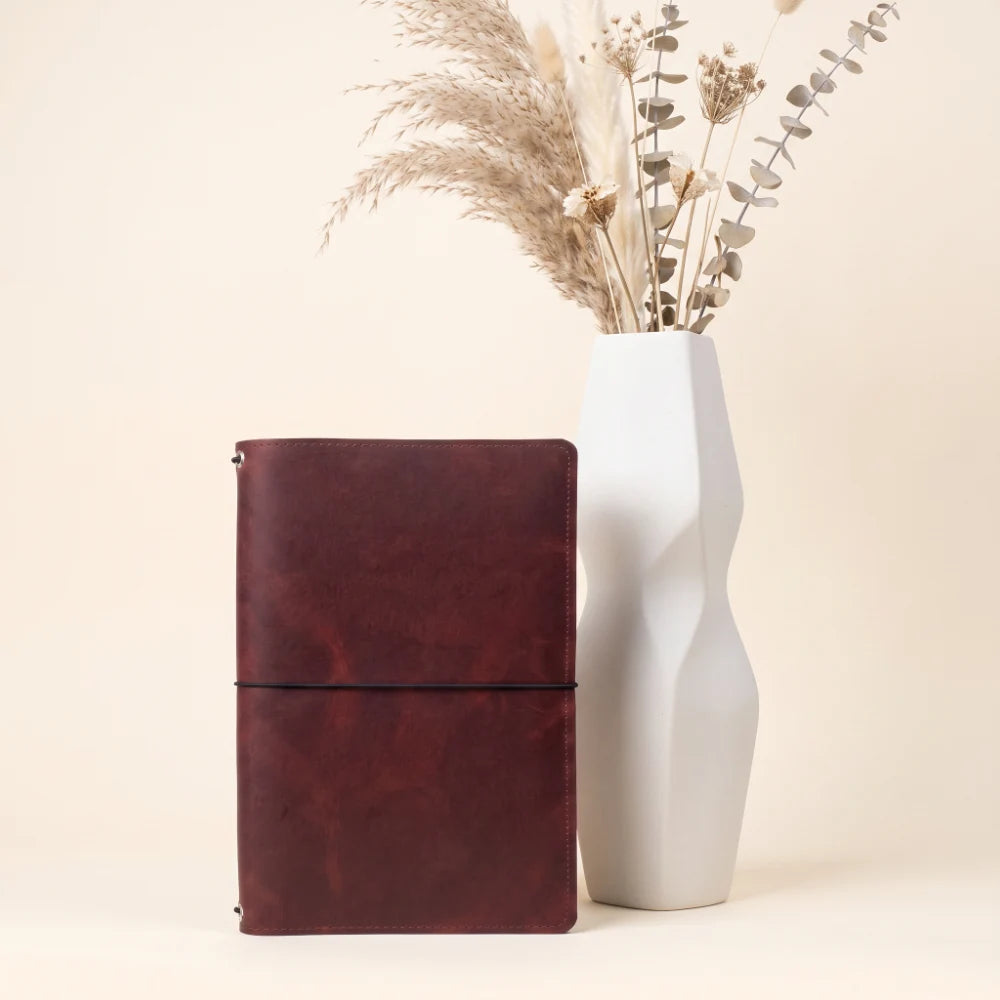 Genuine leather cover designed to hold three refillable notebooks using elastic bands.