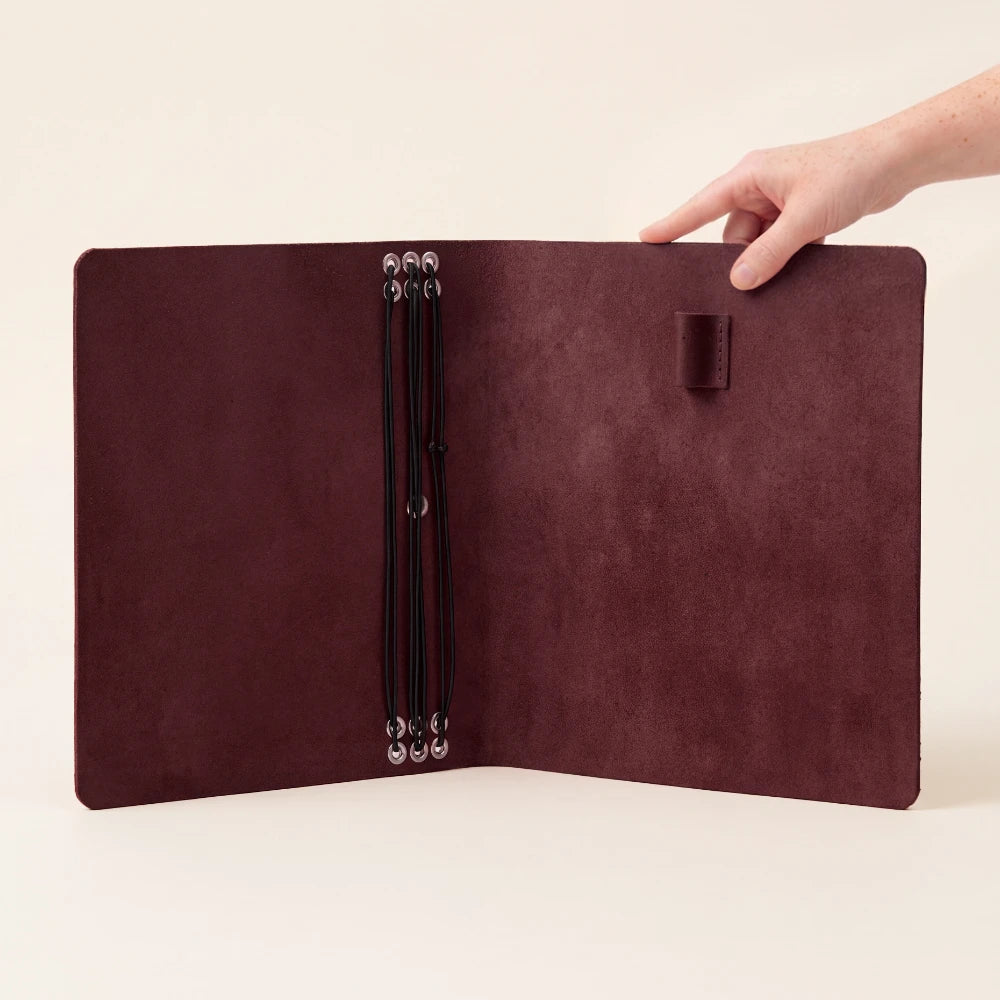 Hand-finished natural leather journal holder with six elastic bands for paper refills.