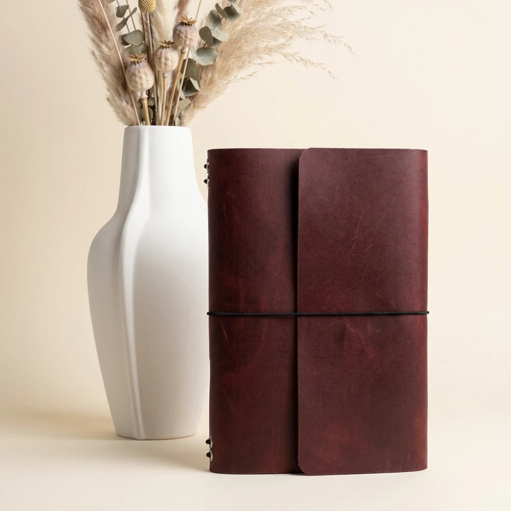 Refillable leather notebook sleeve with six elastic holders and integrated pen storage.
