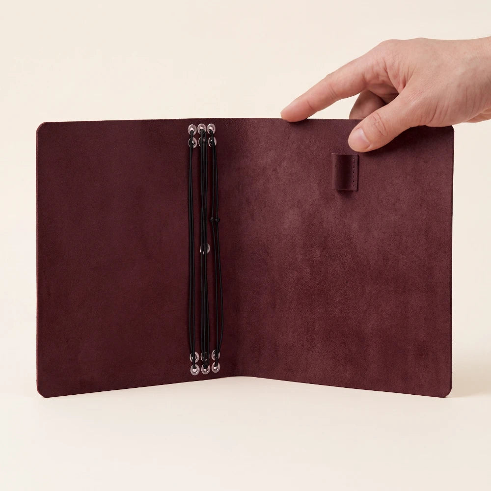 Genuine leather refillable notebook cover designed for six inserts and a pen.