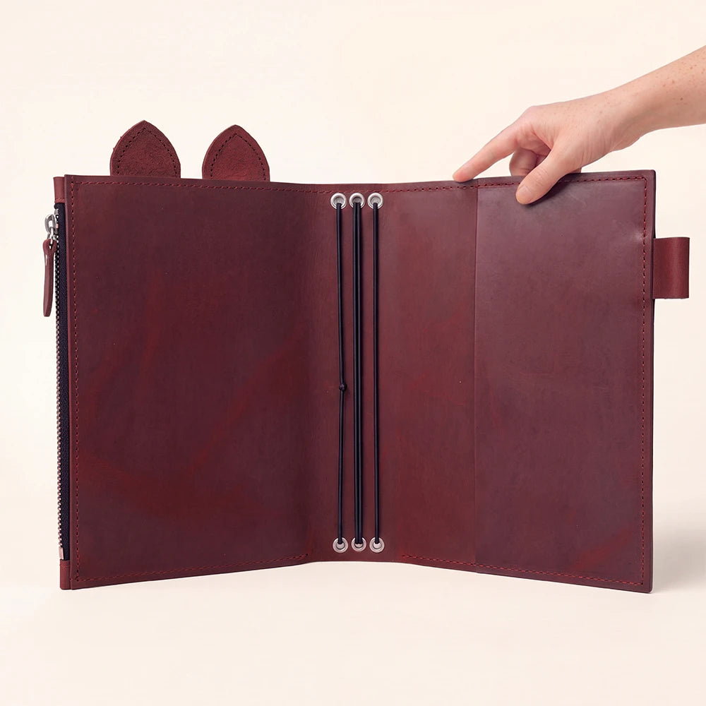 Genuine leather journal holder with decorative upper tabs and a convenient pen loop.