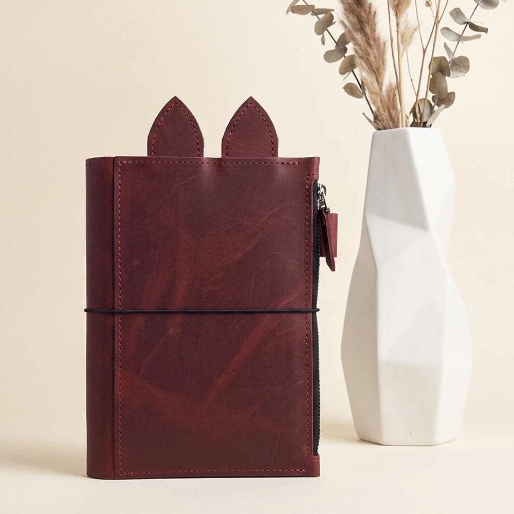 Natural leather notebook holder featuring detailed stitching and flexible interior organization.