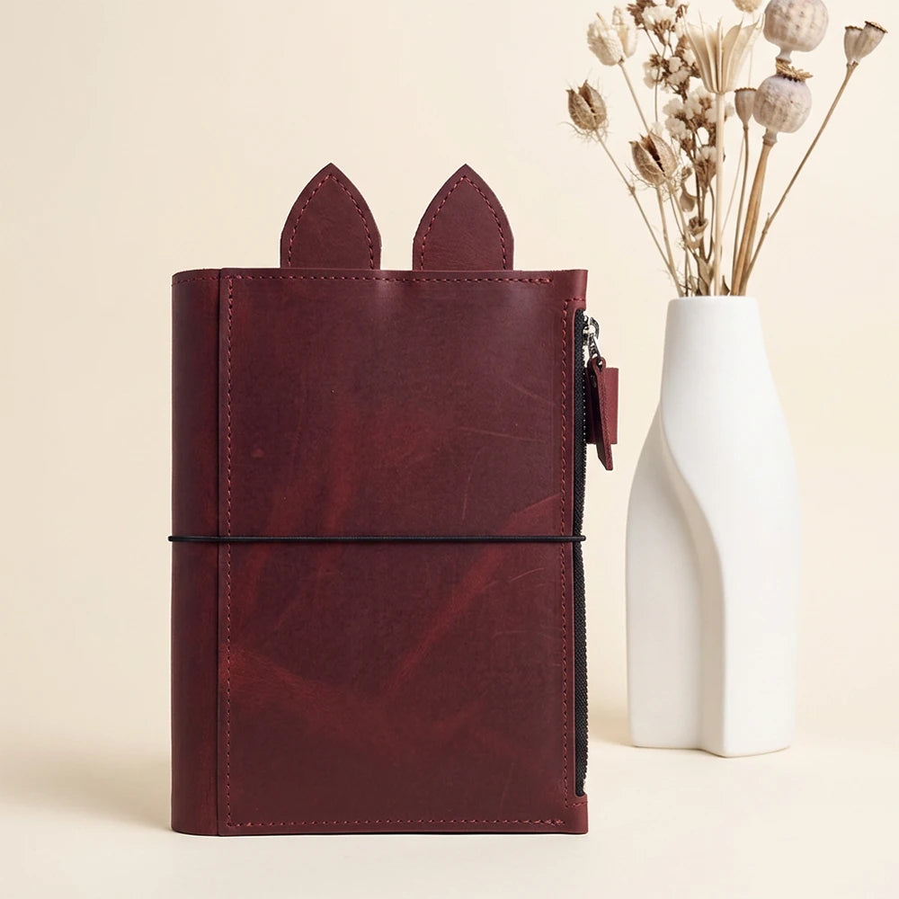 Natural leather notebook organizer with large zippered compartment, pen holder, leather ears, and elastic bands.