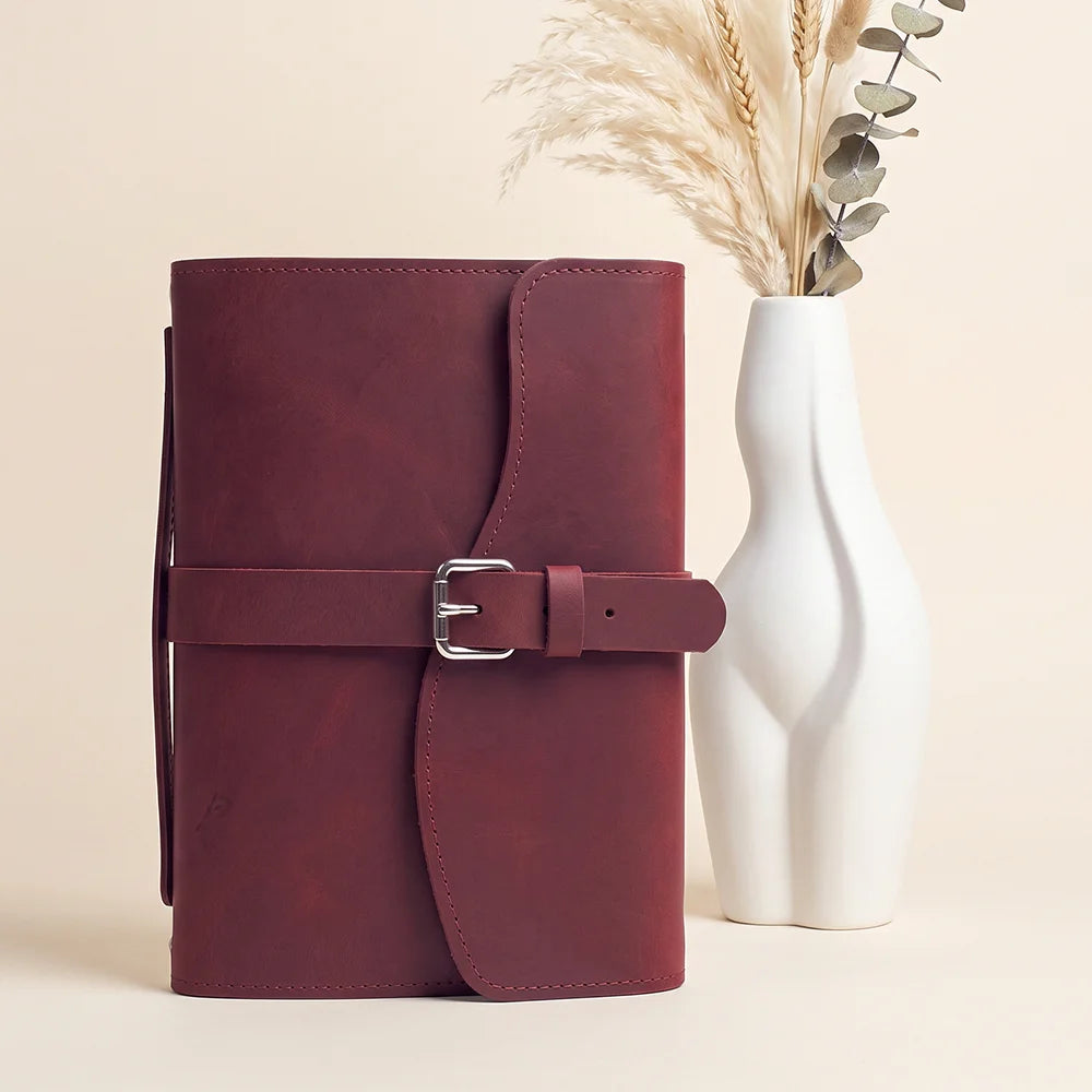 Leather journal carrier designed with storage pockets, secure pen loop, integrated marker, and practical handle.