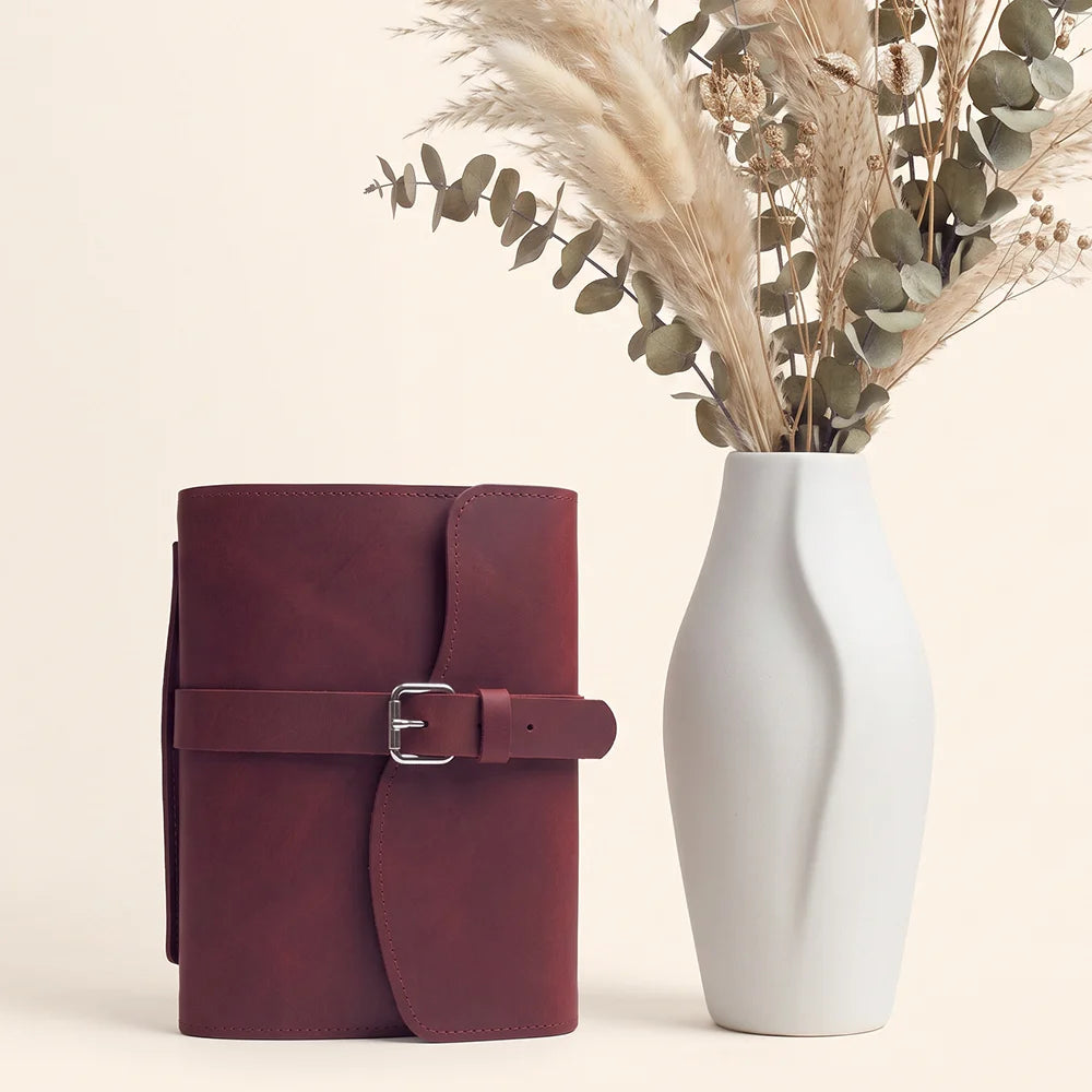 Premium leather notebook holder with useful storage compartments, pen loop, sewn-in bookmark, and carrying strap.