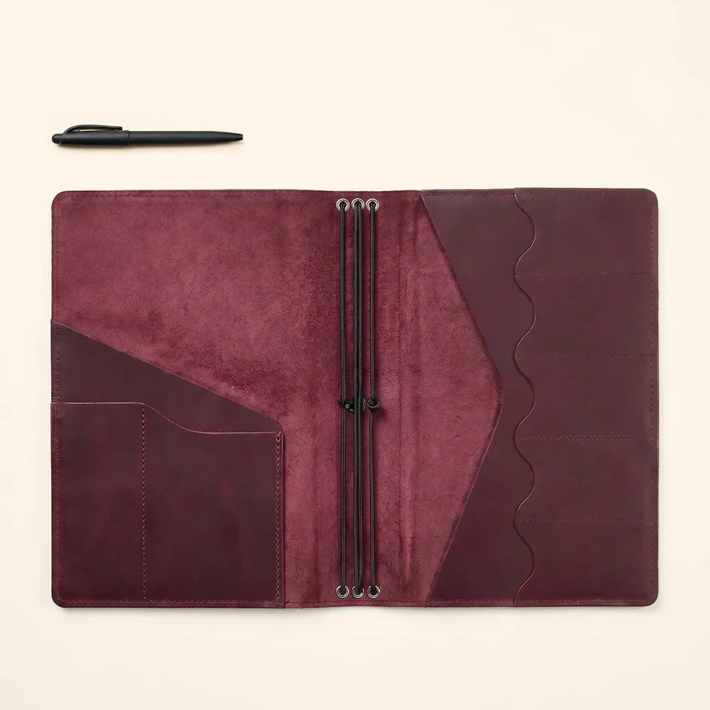 Handmade leather journal cover featuring organized compartments and notebook retaining elastics.