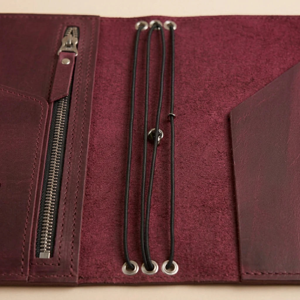 Close-up of a maroon leather journal with zipper and lanyard