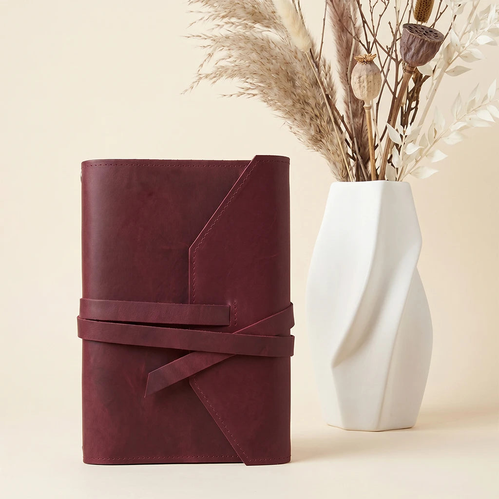 Practical leather notebook holder with elastic straps and integrated pen accessory loop.