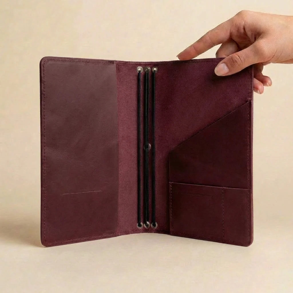 Burgundy leather wallet held open by a hand on a beige background